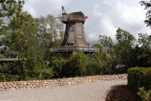 un moulin à vent dans un jardin avec un mur en pierre dans l'établissement Mühlen Kate St. Peter Ording, à Garding