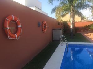 チクラナ・デ・ラ・フロンテーラにあるChalet Martinのオレンジ色の救命具が置かれた家の隣にあるスイミングプール