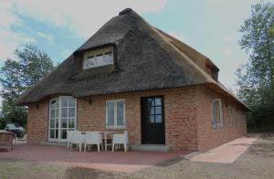 une maison au toit de chaume avec une table et des chaises dans l'établissement Mühlen Kate St. Peter Ording, à Garding