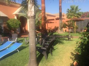 een tuin met stoelen en palmbomen en een huis bij Chalet Martin in Chiclana de la Frontera