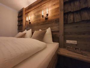 a bed in a room with a wooden wall at HIESERHOF - Superior Alpine Apartments in Heiligenblut