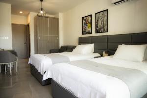 two beds in a hotel room with white sheets at Jimmy's Suites in Larnaca