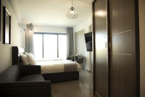a bedroom with a bed and a couch and a window at Jimmy's Suites in Larnaca