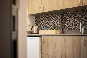 a kitchen with wooden cabinets and a white refrigerator at Jimmy's Suites in Larnaca