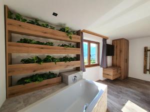 La salle de bains est pourvue d'une baignoire avec des plantes sur le mur. dans l'établissement HIESERHOF - Superior Alpine Apartments, à Heiligenblut