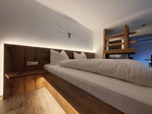 a bedroom with a bed with a wooden headboard and a ladder at HIESERHOF - Superior Alpine Apartments in Heiligenblut