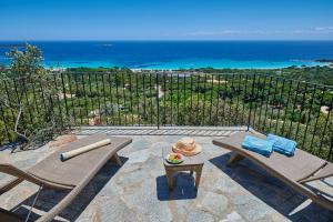 d'une terrasse avec 2 chaises et une table et vue sur l'océan. dans l'établissement Résidence Belvedere de Palombaggia, à Porto-Vecchio