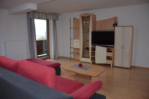 sala de estar con sofá rojo y TV en Bauernhof Grafenhof, en Ebbs