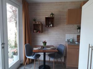 a kitchen with a table and chairs and a window at De Aagt Tuyn in Schoorl