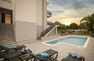 een villa met een zwembad en tuinmeubilair bij Luxury Apartments Villa Lacrima in Šilo