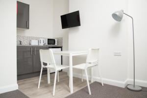貝肯漢的住宿－TLK Apartments & Hotel - Beckenham High Street，厨房配有白色的桌子和白色的椅子