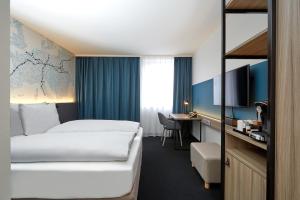 um quarto de hotel com uma cama e uma secretária em H4 Hotel Leipzig em Leipzig