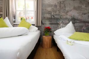 2 Betten in einem Zimmer mit weißer Bettwäsche und grünen Kissen in der Unterkunft Apartments Ante Portas in Salzburg