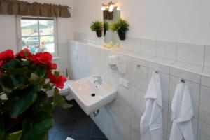 a white bathroom with a sink and red flowers at Apartments Ante Portas in Salzburg