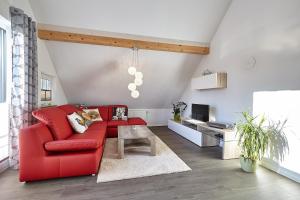 een woonkamer met een rode bank en een tafel bij Exklusive Ferienwohnung auf dem Romanshof - Naturidylle pur - Nebengebäude in Loßburg