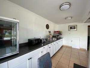 uma cozinha com armários brancos e um balcão preto em Royal Inn Richmond Hill- Savannah I-95 em Richmond Hill