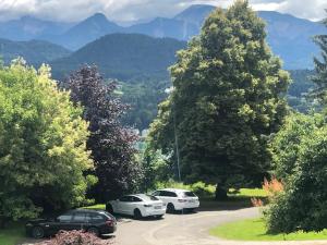drei Autos auf einem Parkplatz mit Bergen im Hintergrund geparkt in der Unterkunft Velden View Ferienwohnung mit großer Sonnenterrasse und See- und Karawankenblick in Velden am Wörthersee