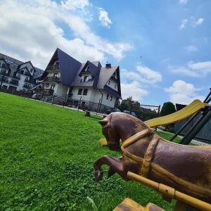 a statue of a dog in the grass in front of a house at Chata pod Jemiołą in Zakopane