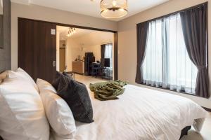 Bijou Suites Vivre في أوساكا: غرفة نوم مع سرير أبيض كبير مع نافذة كبيرة