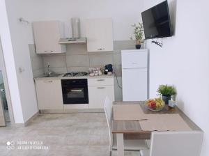 a kitchen with white cabinets and a table with a dining room at La Casa di Katia in Canicattì