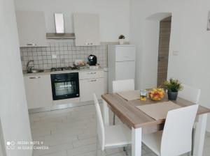 a kitchen with a wooden table and white cabinets at La Casa di Katia in Canicattì