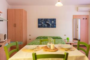 a room with a table with green chairs and a bed at Residence Le Pavoncelle in Santa Teresa Gallura