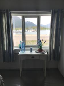 a table in front of a window with a view of the beach at Laukvika rorbuer in Laukvik