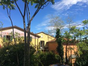 a yellow house with trees in the foreground at B&B Monte Donato in Bologna