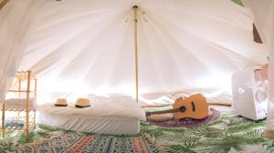 桃園區的住宿－晃晃印地安帳棚露營區，一间卧室配有一张床,帐篷内备有吉他
