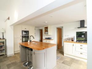 uma cozinha com armários brancos e um balcão de madeira em The Coach House em Sleaford