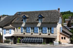 uma casa velha com persianas azuis numa rua em Logis Hôtel Restaurant L'Auberge du Chateau em Muret-le-Château