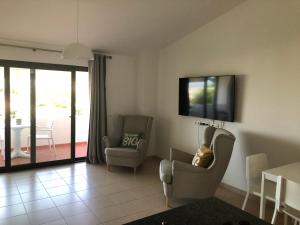 ein Wohnzimmer mit 2 Stühlen und einem TV an der Wand in der Unterkunft Victory Village Apartamento in Quinta do Lago