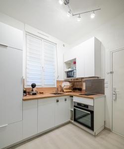 a kitchen with white cabinets and a counter top at ***La Pétillante*** à 2 pas de la Gare et du Centre ville in Reims