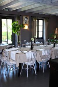 una sala da pranzo con tavoli bianchi e sedie bianche di Logis Hôtel Restaurant L'Auberge du Chateau a Muret-le-Château