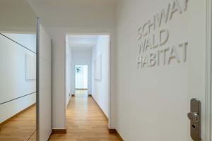 a hallway with white walls and wooden floors and a mirror at Schwarzwald Loft in Baden-Baden