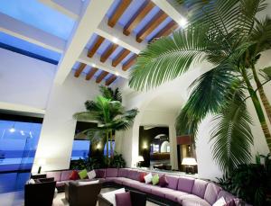 a living room with a purple couch and a palm tree at Santa Tecla Palace in Acireale