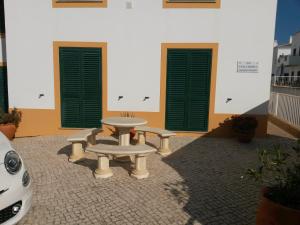 une table et deux bancs devant un bâtiment dans l'établissement Casa Carmela, à Burgau