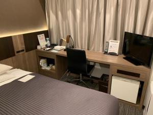 Ochanomizu Inn في طوكيو: غرفة في الفندق مع مكتب وبه جهاز كمبيوتر وسرير