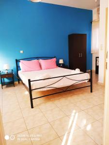 a bedroom with a bed with pink pillows and a blue wall at Apartments Onar in Argostoli