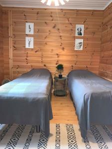 two beds in a room with wooden walls at Villa Taikuri in Kyläniemi