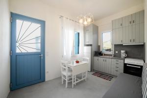a kitchen with a blue door and a white table at Amphoras Apartments in Korissia