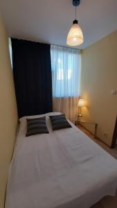 um quarto com uma grande cama branca com almofadas pretas em W samym Centrum na Grzybowskiej em Varsóvia