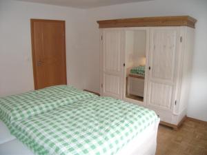 a bedroom with a green and white bed and a cabinet at Ferienwohnung Annemarie in Gernsbach