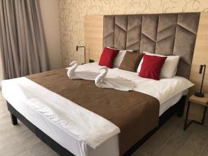 a large bed with white sheets and red pillows at Aquamarine Hotel&Spa in Plyakho