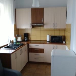 a small kitchen with white cabinets and a sink at Centrum - Mala Apartamenty in Wejherowo