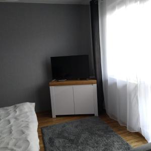 a bedroom with a bed and a flat screen tv at Centrum - Mala Apartamenty in Wejherowo