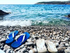 un paio di infradito e scarpe su una spiaggia rocciosa di Apartment Adriatic Blue a Tivat