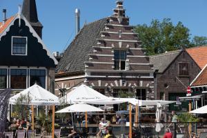 eine Gruppe von Tischen mit Sonnenschirmen vor einem Gebäude in der Unterkunft Harbour Suites Boutique Hotel in Monnickendam