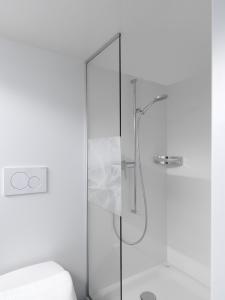 une douche avec une porte en verre à côté des toilettes dans l'établissement Alpenheim, à Teufen