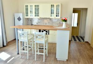 a kitchen with white cabinets and a table with stools at Apartmány Vila Mánička in Kácov